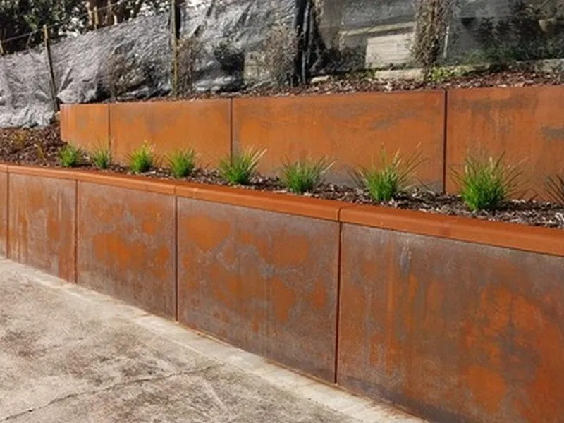 Modular retaining wall built from 100% recycled plastic panels with a weathered rust-effect surface