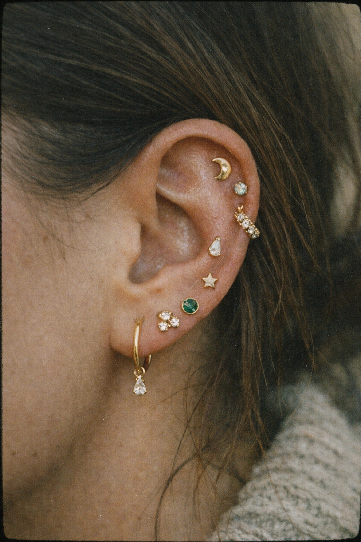 A fully healed curated ear featuring multiple gold studs from a professional body piercing Hixson TN studio.