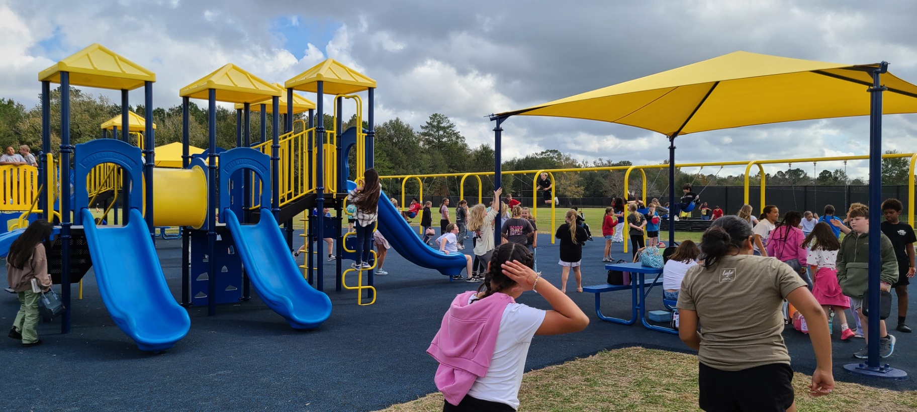 Kids playing on blue and yellow community playground—active, inclusive fun that boosts health and coordination