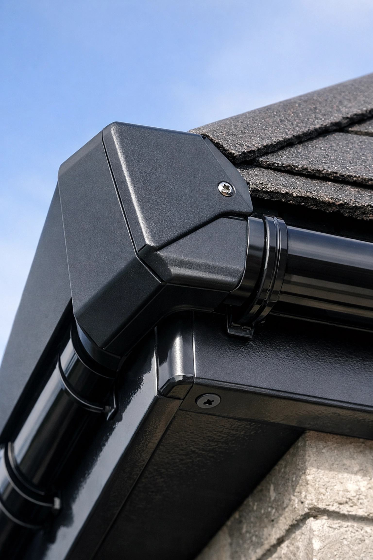 Anthracite dry verge end cap professionally installed to drain roof water into uPVC guttering.