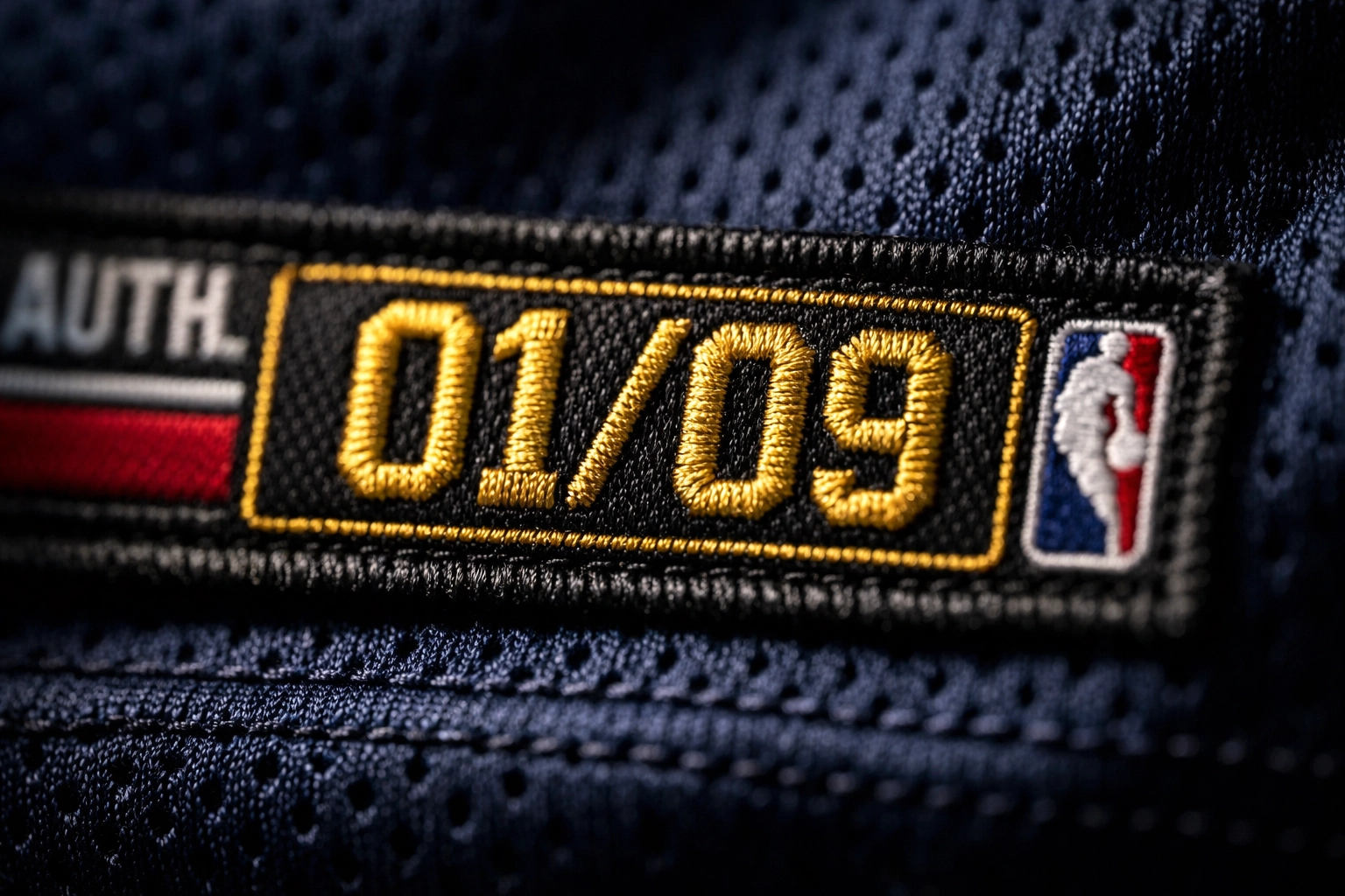 Close-up of a gold embroidered limited edition 01 of 09 tag on a premium sports jersey.