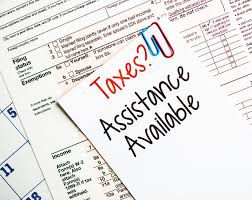 Taxes? Assistance Available - Brick Taxes LLC A notepad with the words 'Taxes? Assistance Available' sits on top of federal tax forms, symbolizing Brick Taxes LLC's professional tax preparation and support services for individuals and businesses dealing with tax filings or IRS inquiries.