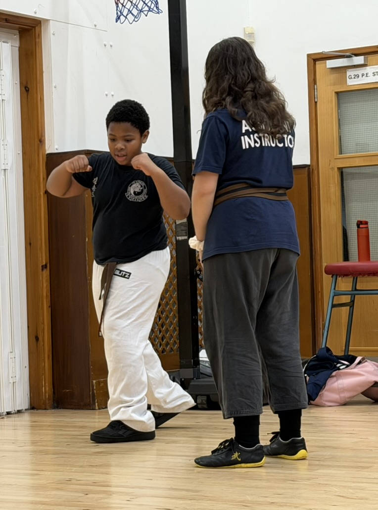 Young martial arts student practicing with instructor supervision