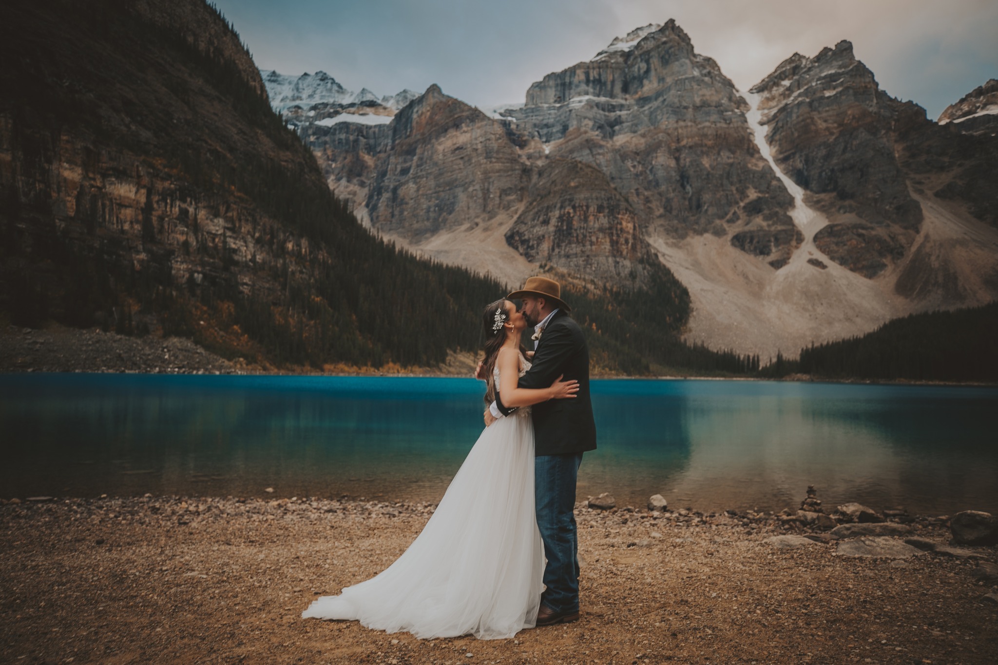 A newlywed couple shares a kiss at Moraine Lake
