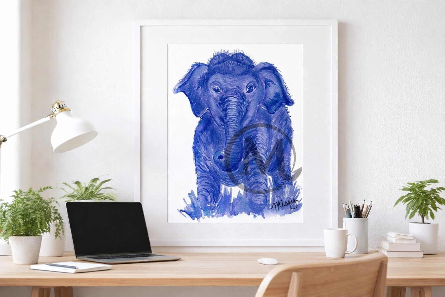 Missy's original Blue Elephant watercolor print displayed in a physical desk frame mockup with watermark and signature visible