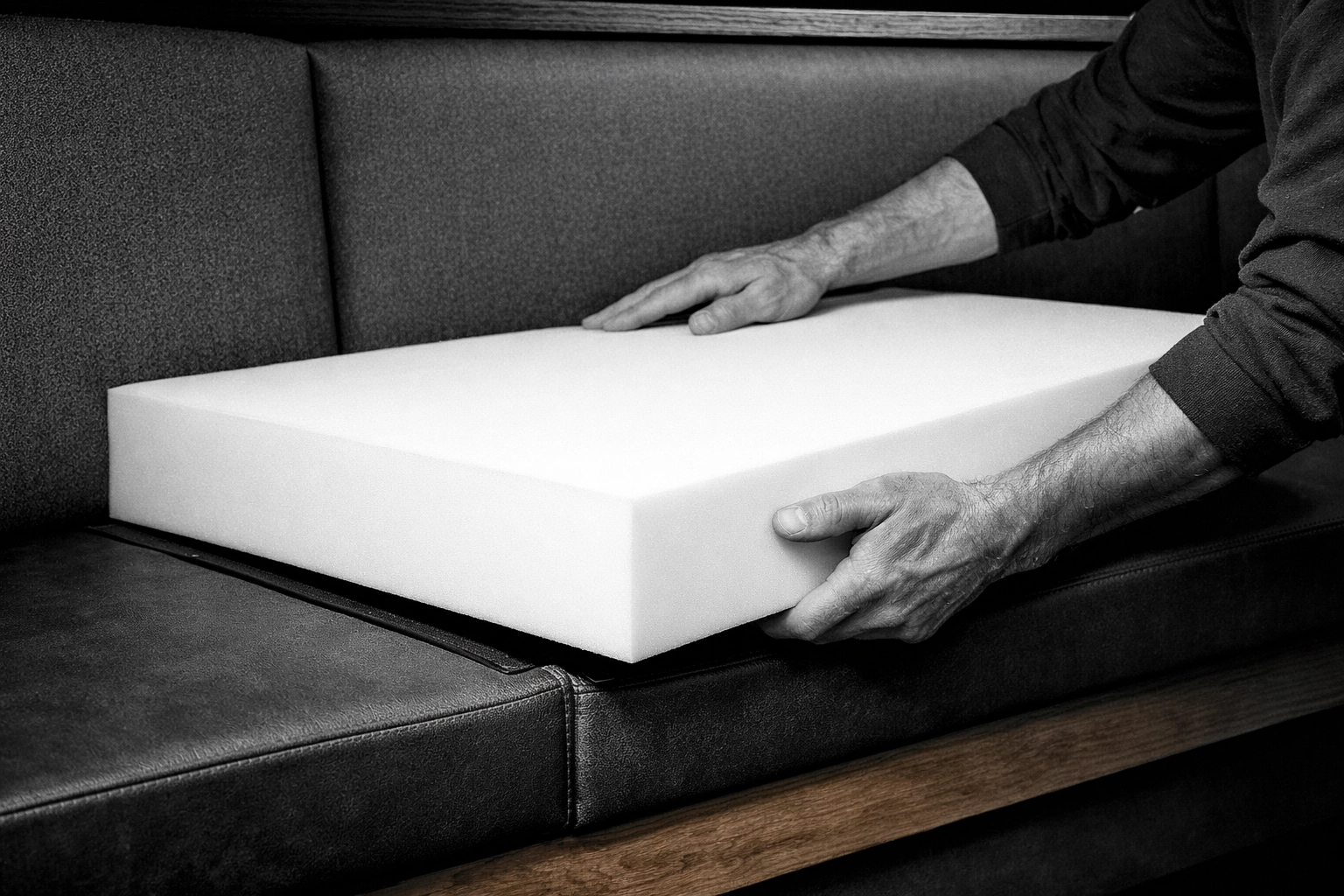 Custom-cut high-density foam cushion being professionally fitted into a commercial restaurant booth.