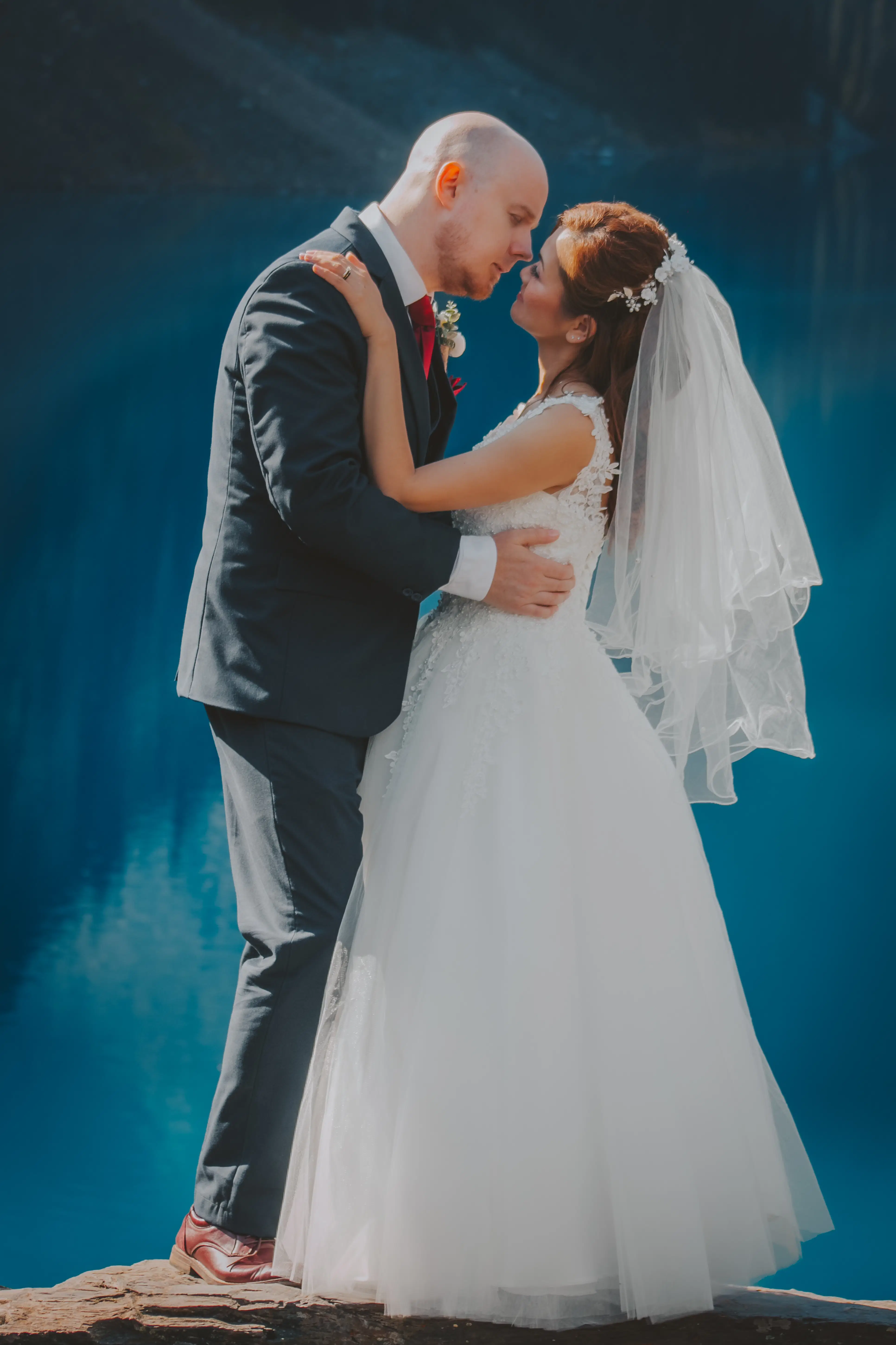 lakeside-embrace-bride-groom-banff-lake.webp