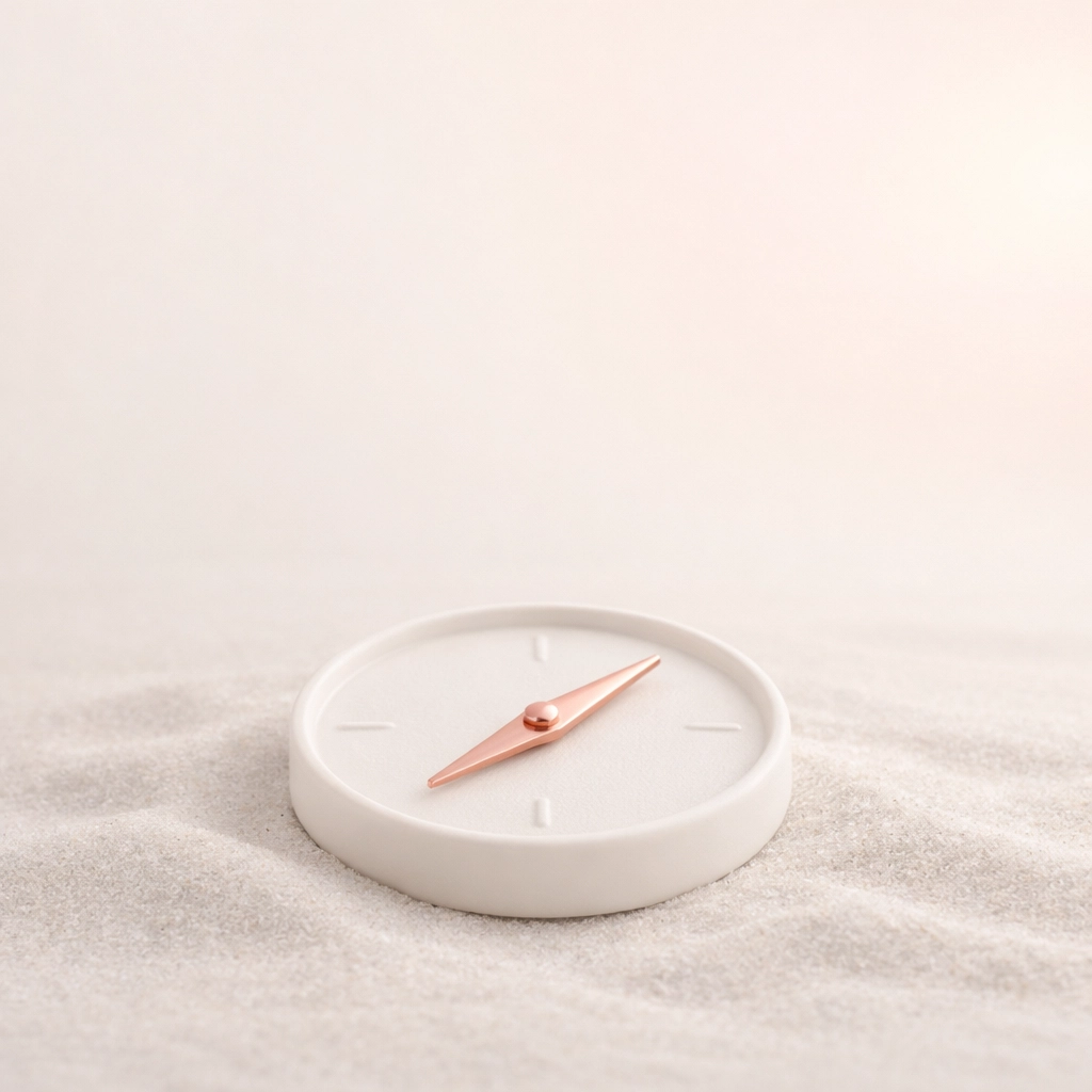 Minimalist compass on sand representing strategic direction for leaders in career transition.
