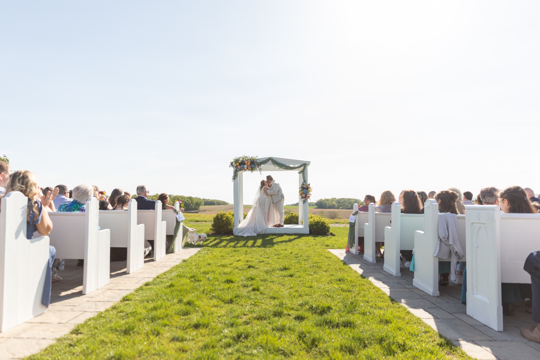 Bride and groom’s first kiss—guests close, emotions high, and the moment unmistakably theirs
