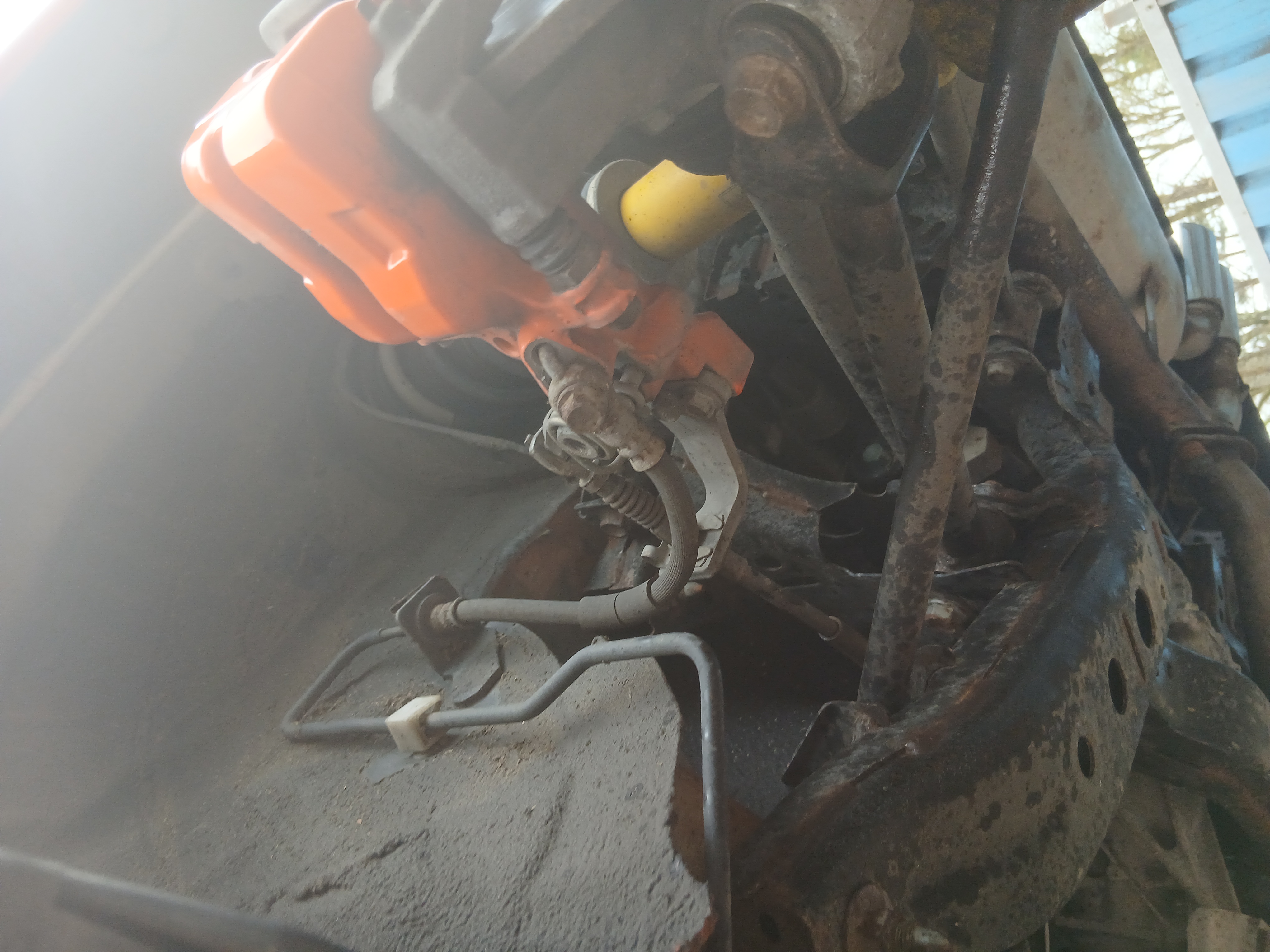 Close-up of a vehicle’s underbody showing suspension and brake lines with visible surface rust