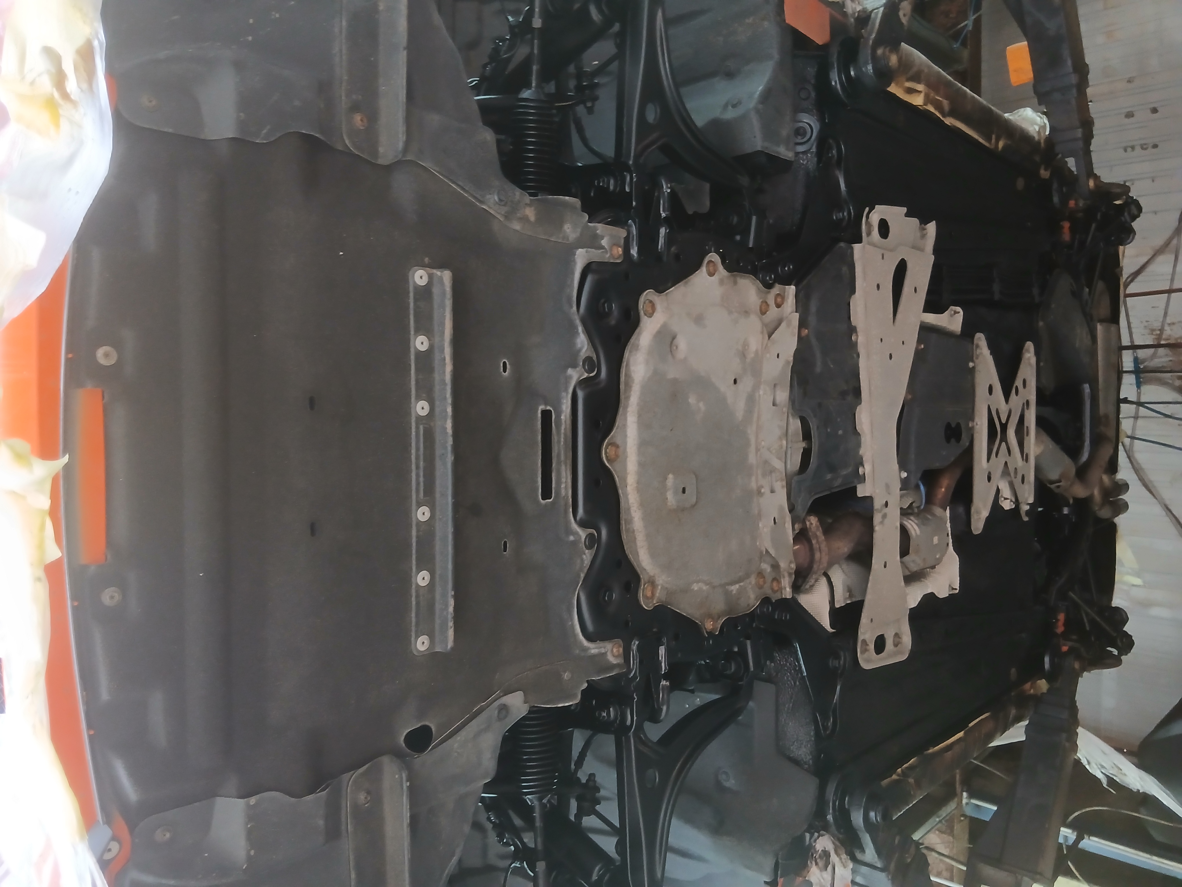 Vehicle underbody viewed from below during rust proofing preparation.