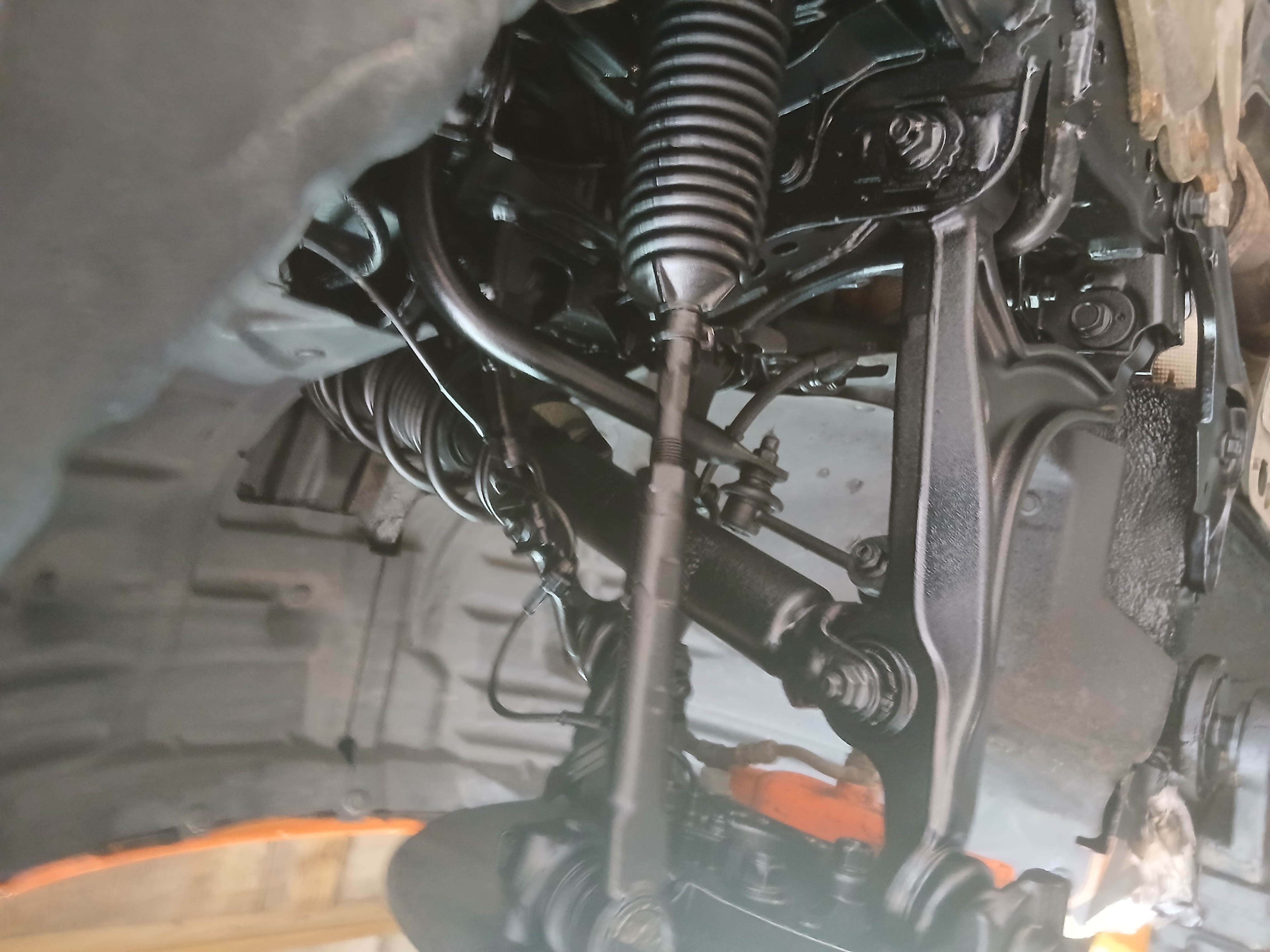 Close-up of a vehicle’s front suspension and steering components following a professional underbody rust proofing treatment.