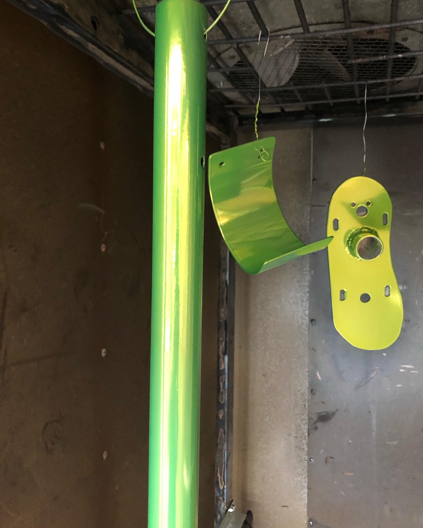 Three metal parts with neon green powder coat