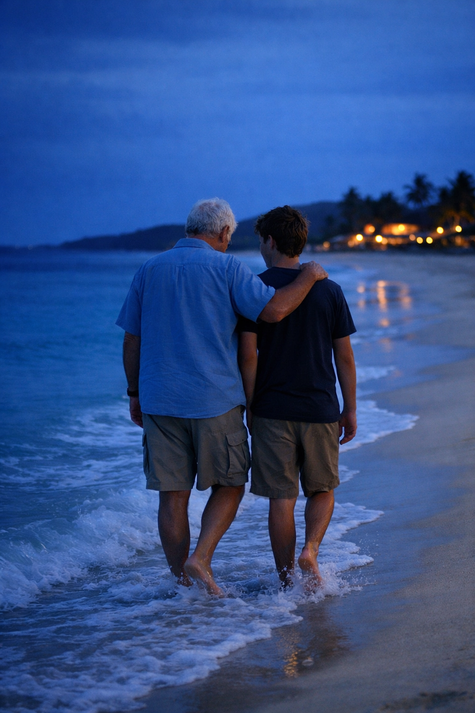 Grandfather and teenage grandson walking on a peaceful Caribbean beach during a family vacation.