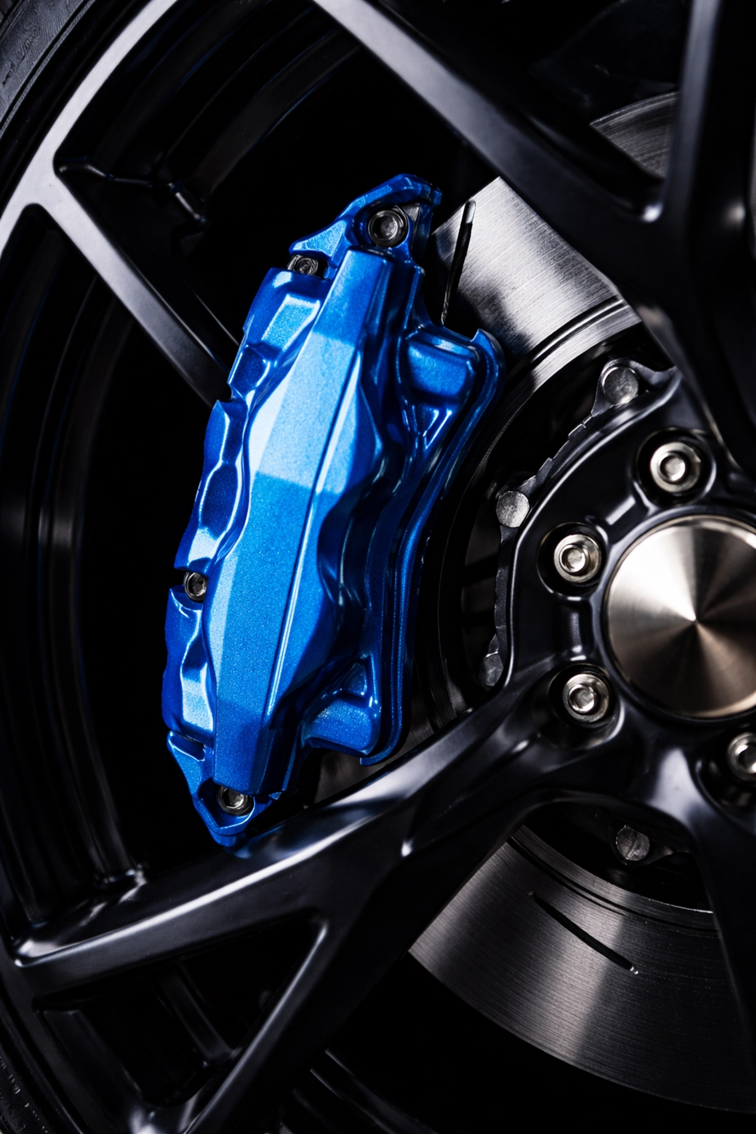Close-up of a powder-coated electric blue brake caliper on a Dodge Charger, highlighting flawless finish.