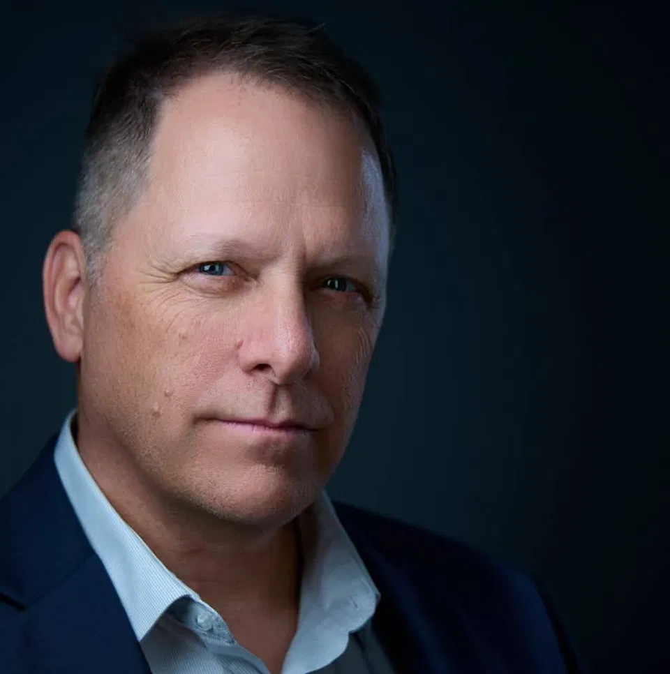 Professional executive headshot featuring a confident middle-aged man in a dark suit, capturing attentiveness and decisiveness