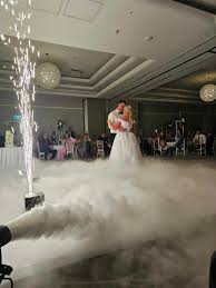 A bride and groom enjoy their first dance surrounded by a low-lying fog effect and sparkling indoor cold sparks