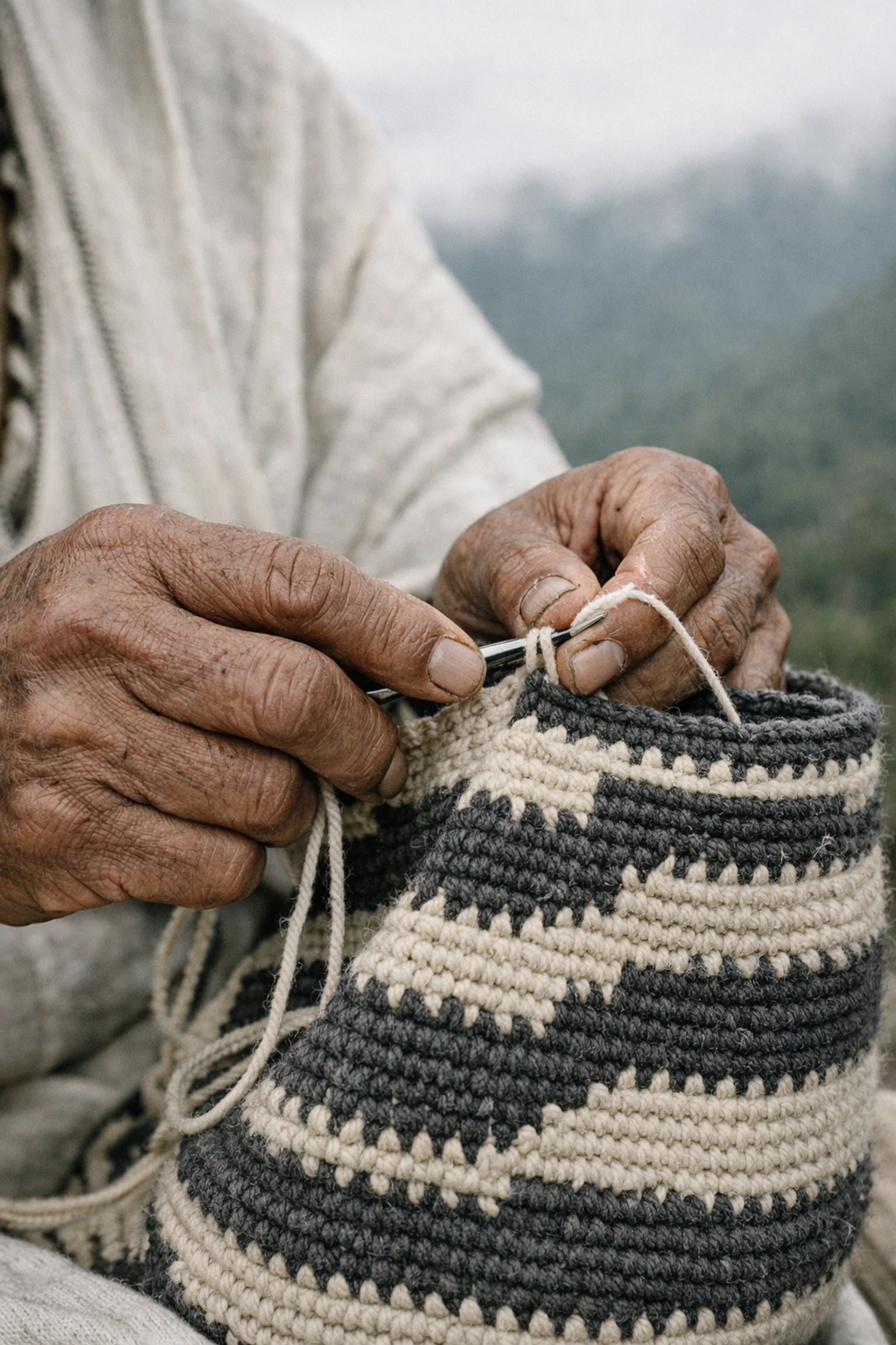Iku artisan hands weaving a traditional mochila backpack with natural fibers in the Sierra Nevada mountains.