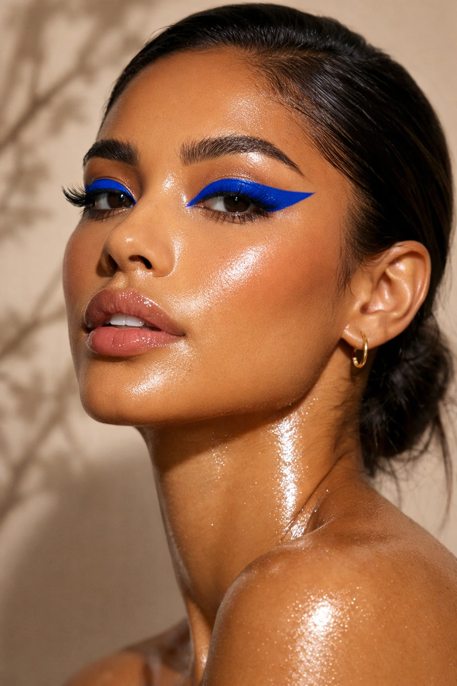 Radiant model with electric blue winged eyeliner and dewy skin showcasing a bold spring makeup trend.