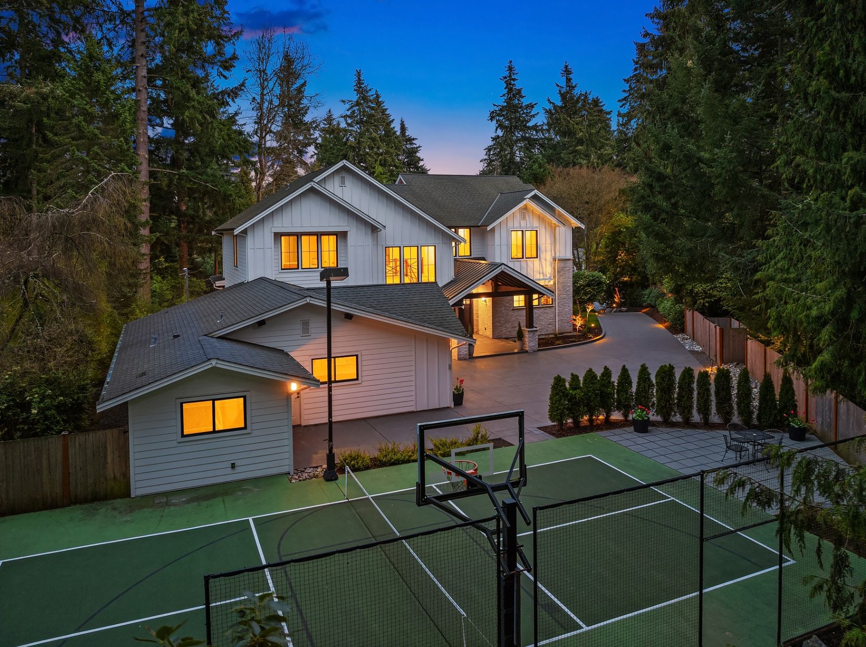 Stunning exterior at dusk with a full-sized multi-use sports court for basketball/pickleball
