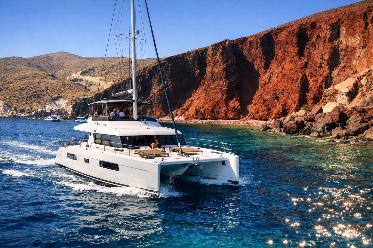 A luxury catamaran cruising past the dramatic volcanic Red Beach cliffs in Santorini, Greece.