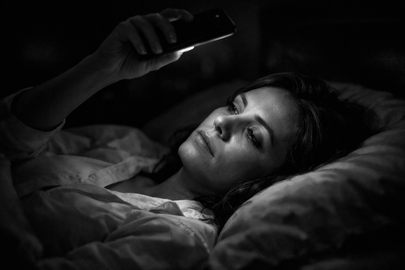 Professional woman experiencing dating app burnout while scrolling in bed late at night