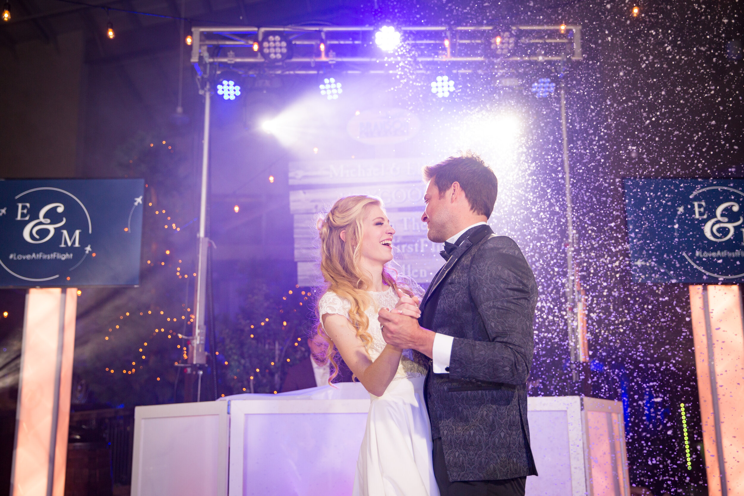 First Dance with Modish Entertainment Bride and groom share their first dance under atmospheric lighting and indoor snow effects. Professional DJ setup and screens personalized with couple's initials create a bespoke, glamorous event backdrop, highlighting Modish Entertainment's signature full-service wedding production.
