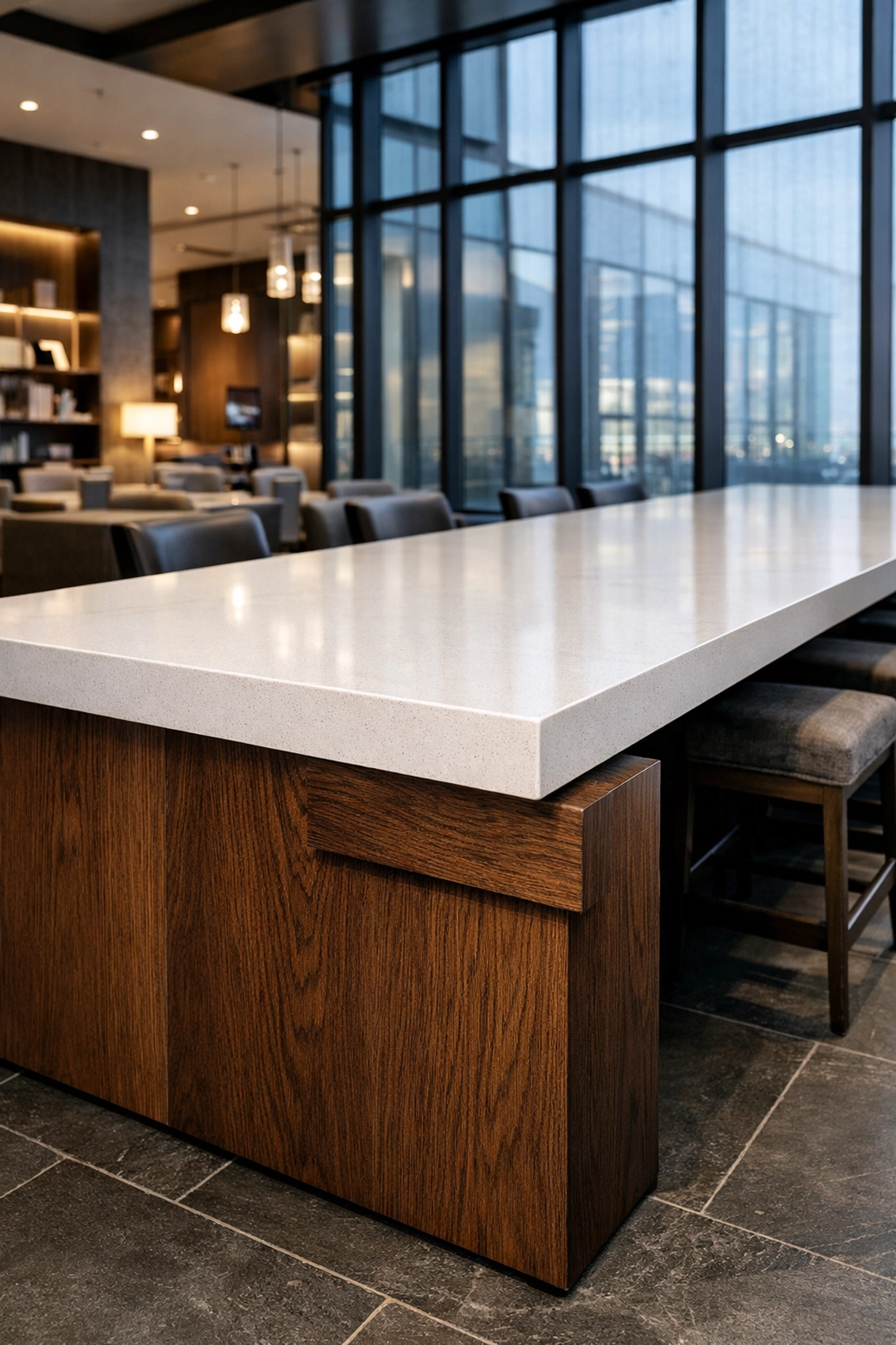High-end quartz and oak communal table in a sleek hotel lounge, showcasing quality commercial furniture for hospitality.