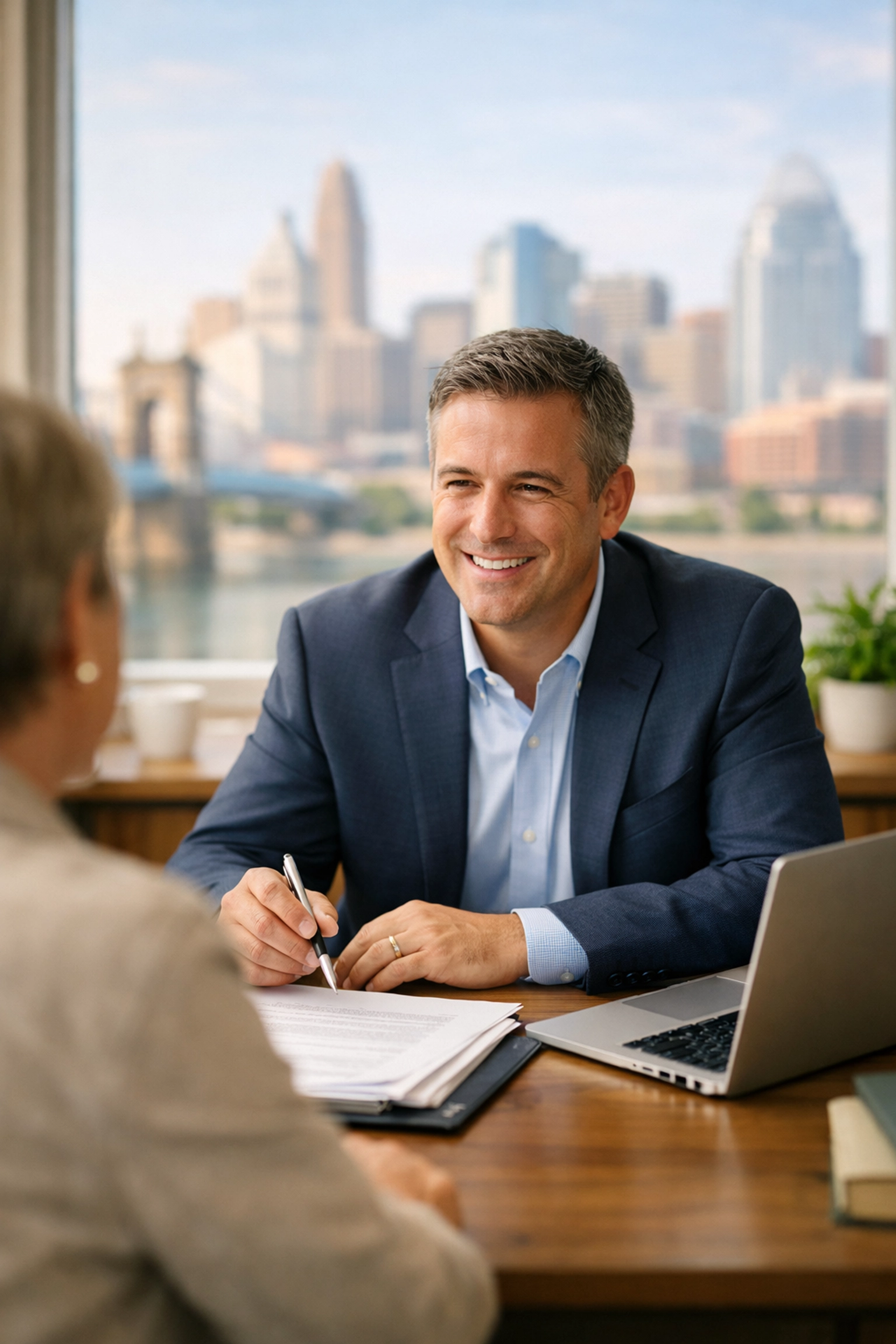 Independent insurance agent meeting with client in Cincinnati office with skyline view