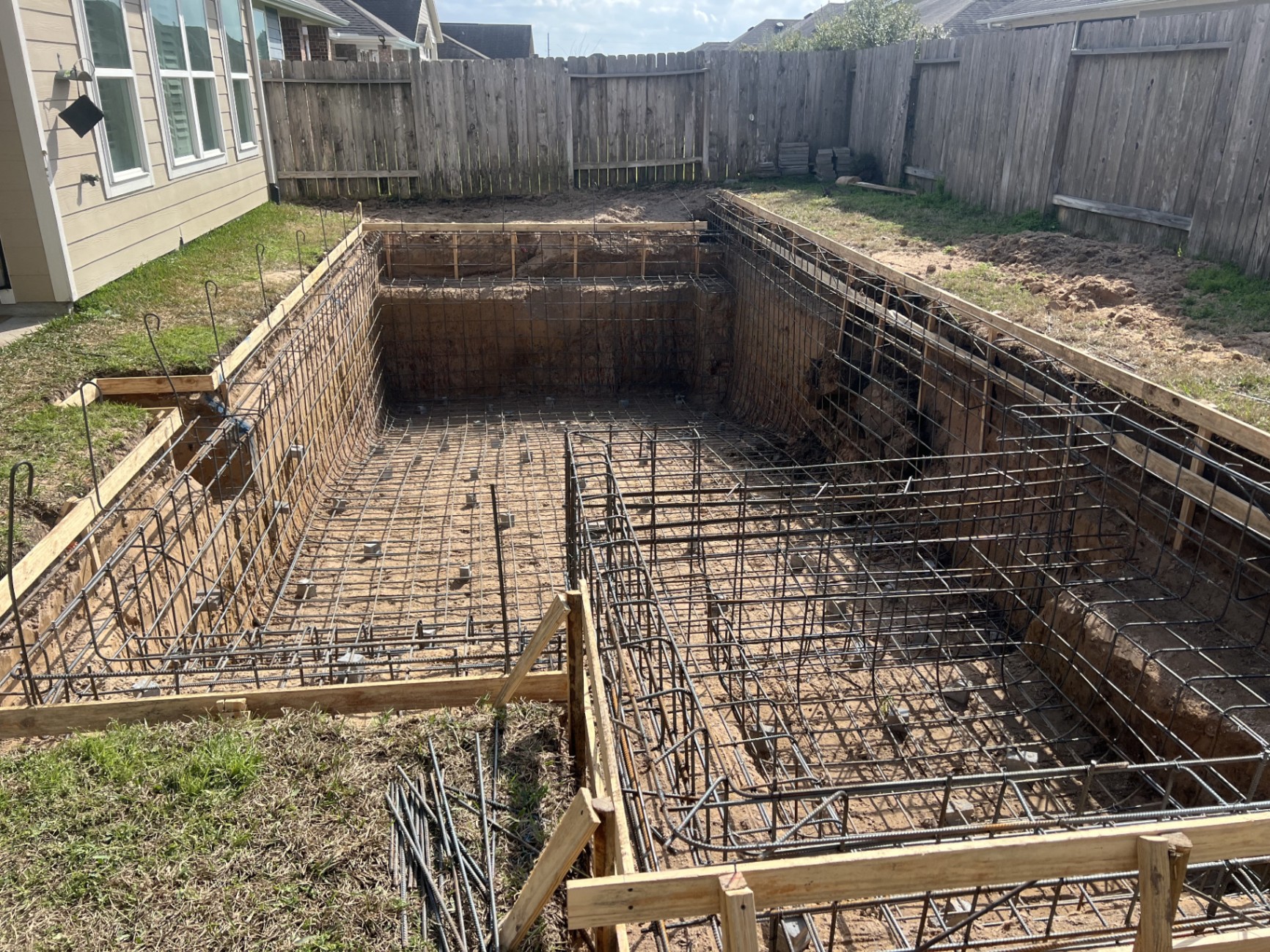 Aerial view of a luxury pool under construction in The Woodlands, Texas, showing early building progress