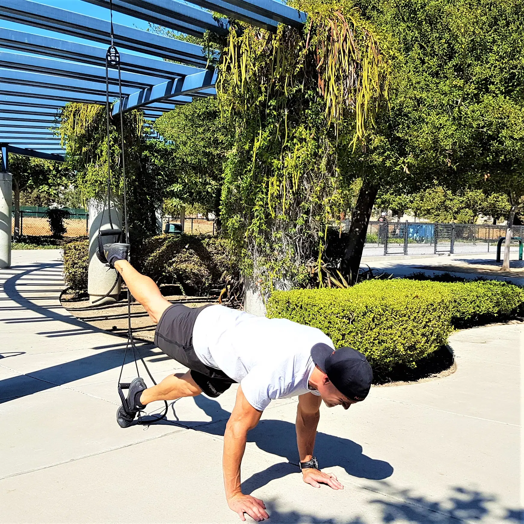 A man performs a plank with leg extension using the NOSSK suspension bodyweight trainer.