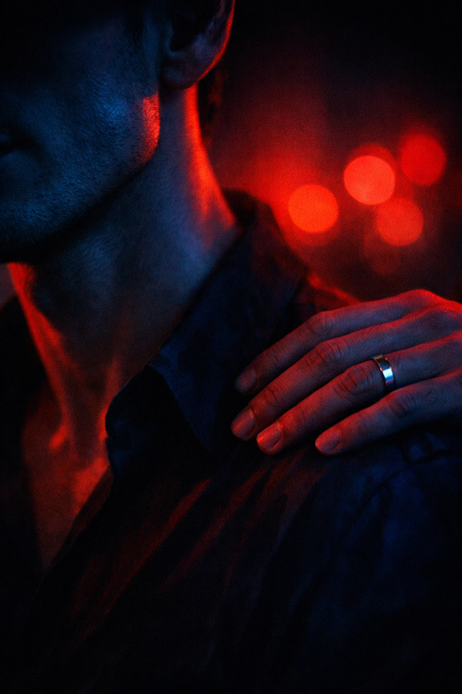 Close-up of an anonymous encounter between two men in a dark club room.