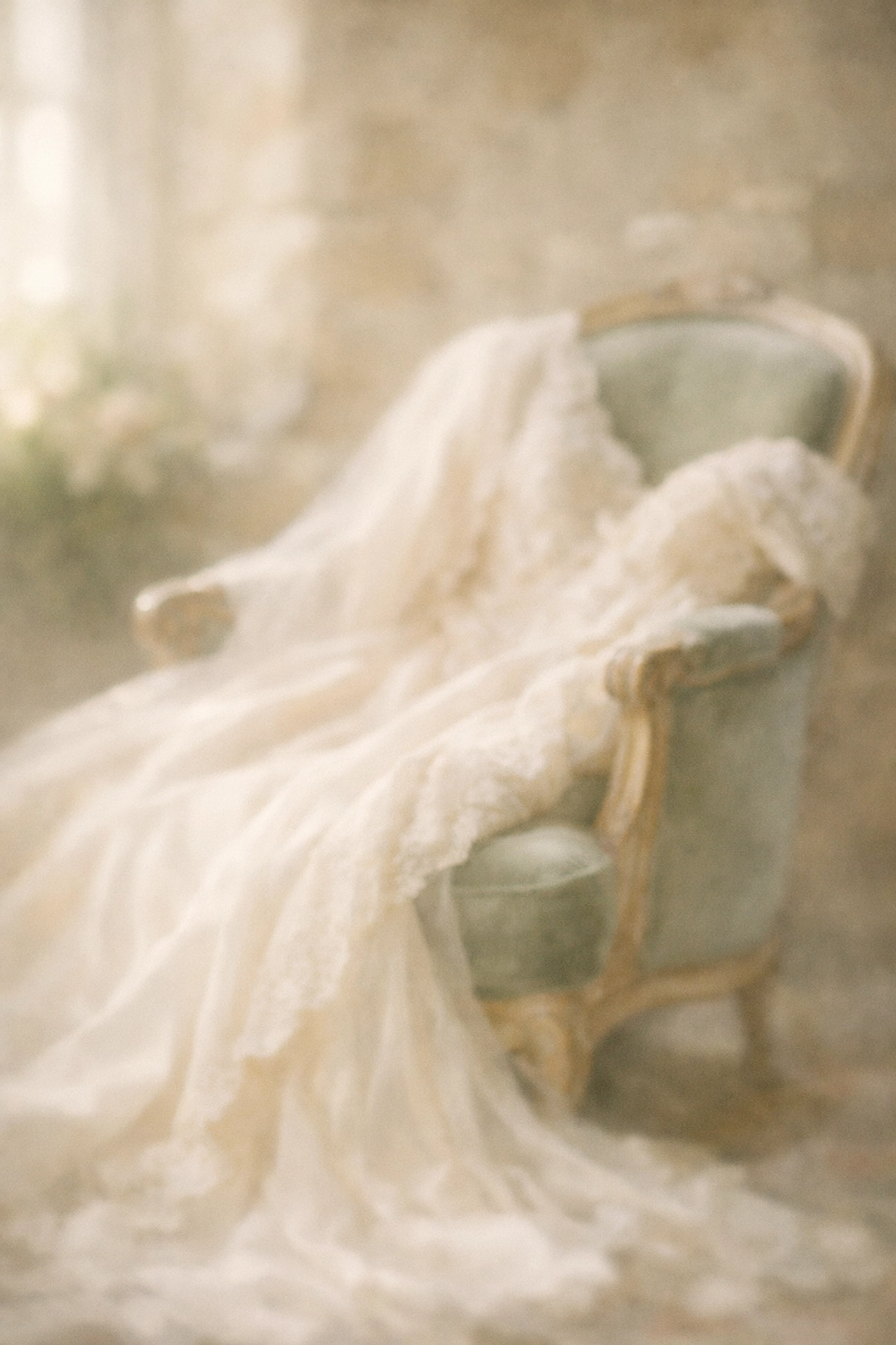 A luxurious bridal gown with delicate lace draped over an antique chair in a historic manor setting.