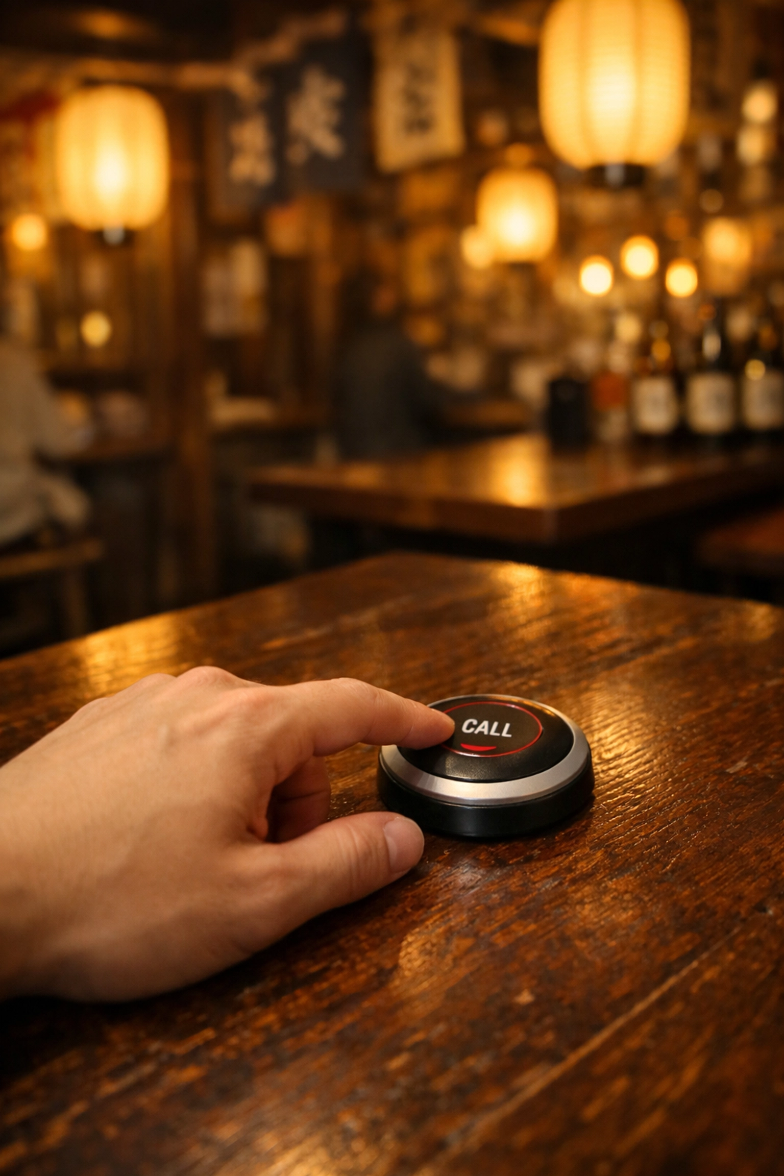 A guest pressing a service call button at a traditional Tokyo izakaya restaurant table.