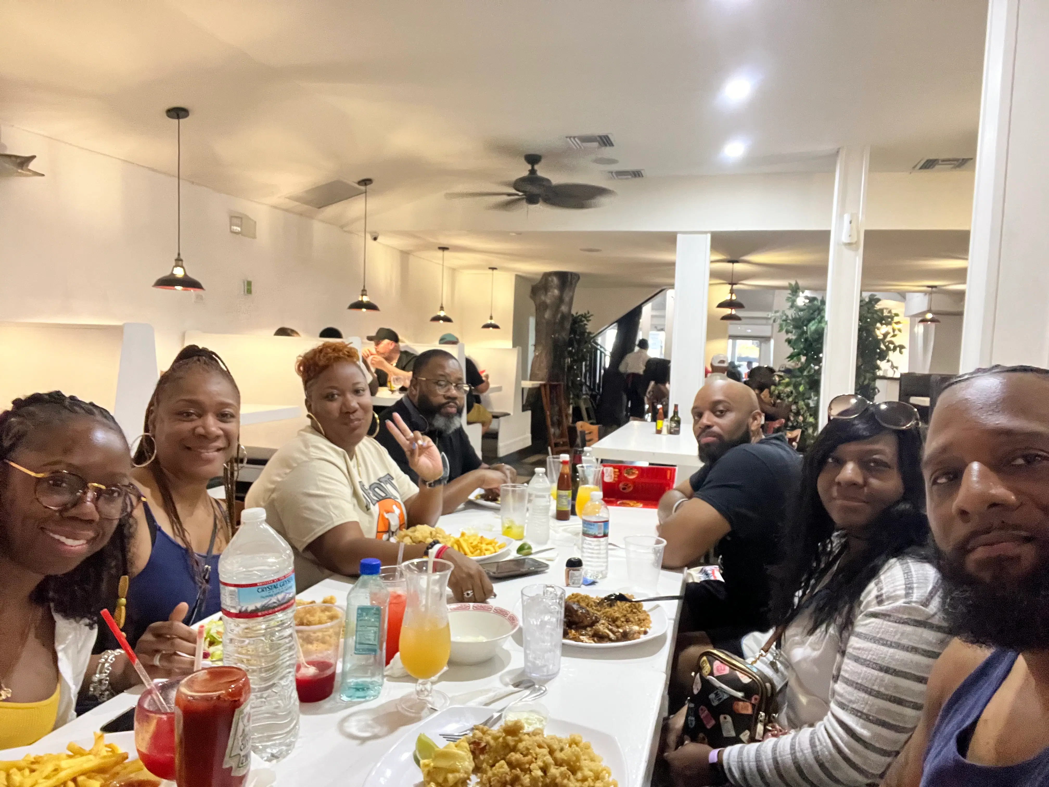 A group of travelers shares a lively meal at a modern, well-lit restaurant, enjoying local cuisine and colorful drinks together.
