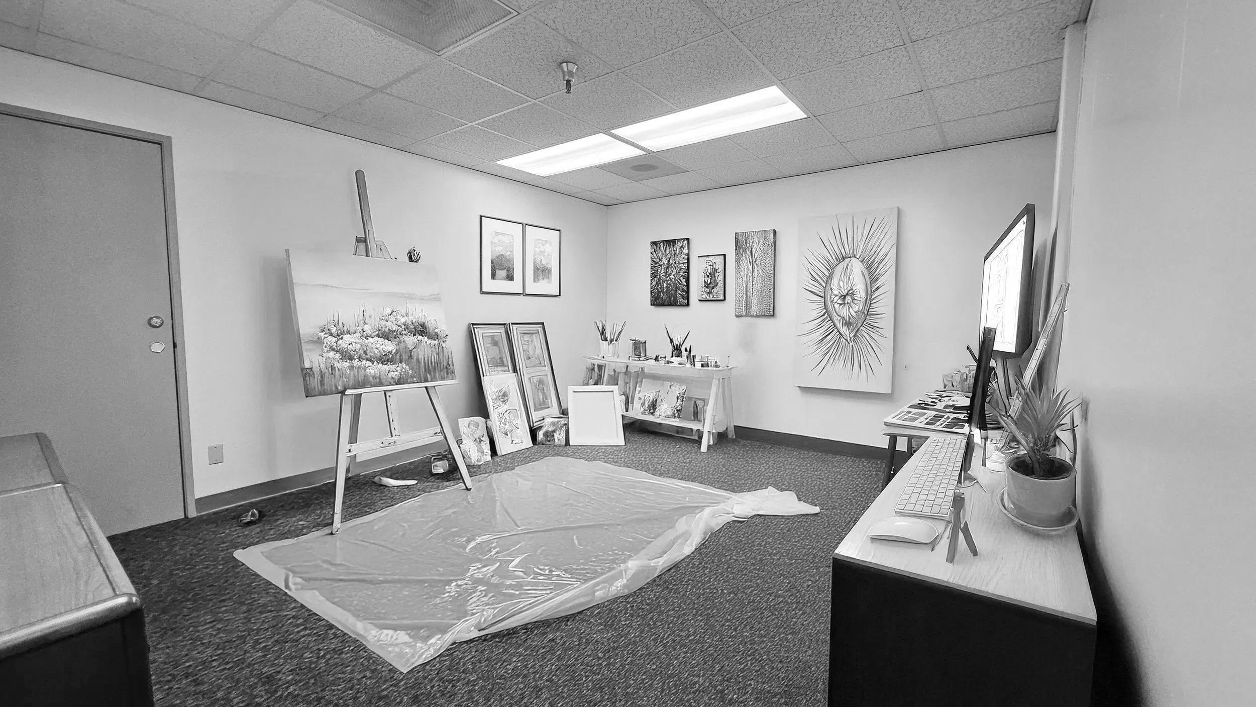 A private rental studio at ArtLabs featuring a professional setup: an easel with a landscape painting, framed artworks, and a clean workstation with a monitor. The photo is crisp and neutral, highlighting the organized and inspiring environment available for instructors.