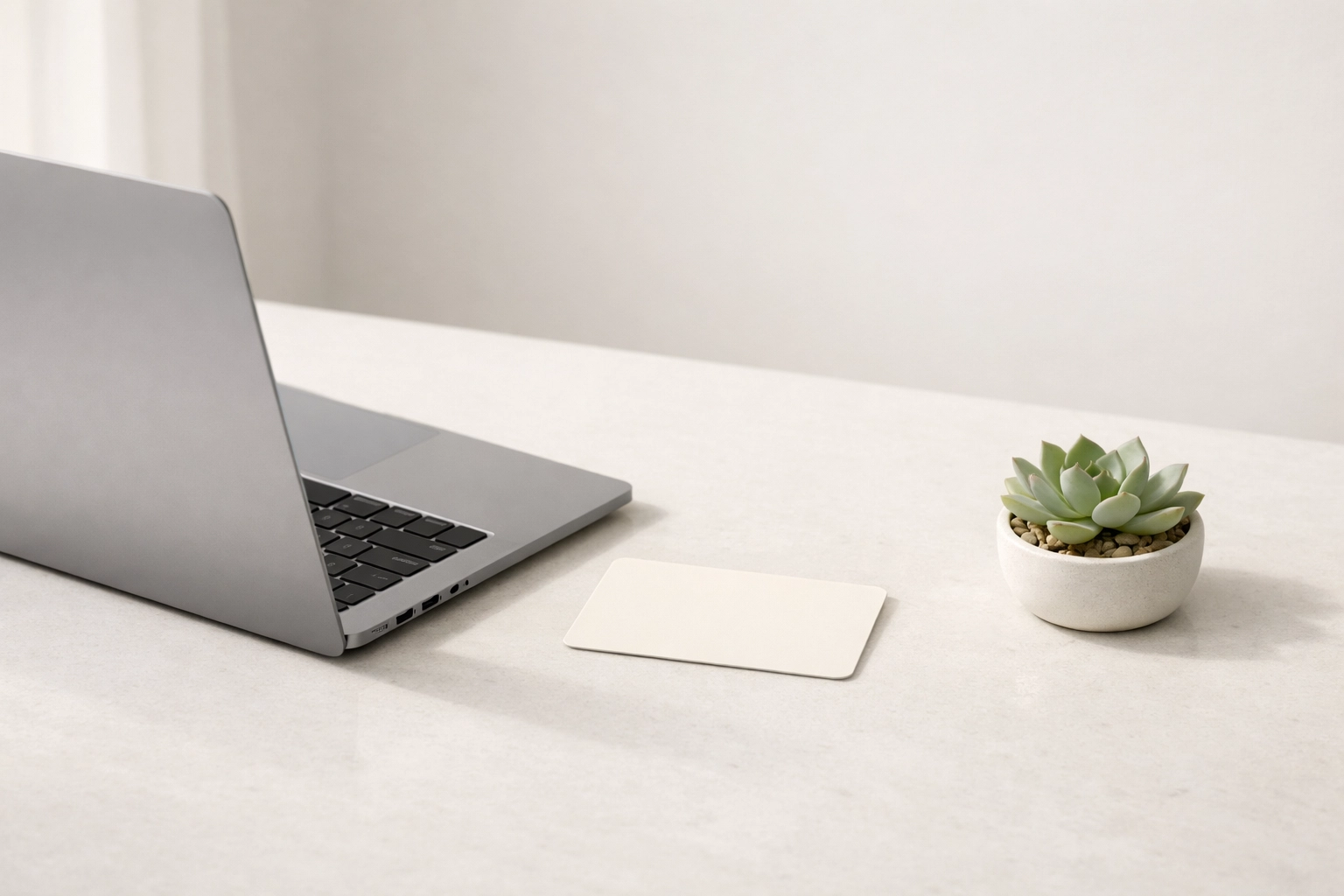 Laptop displaying an integrated hotel PMS and management software on a clean, modern stone desk.