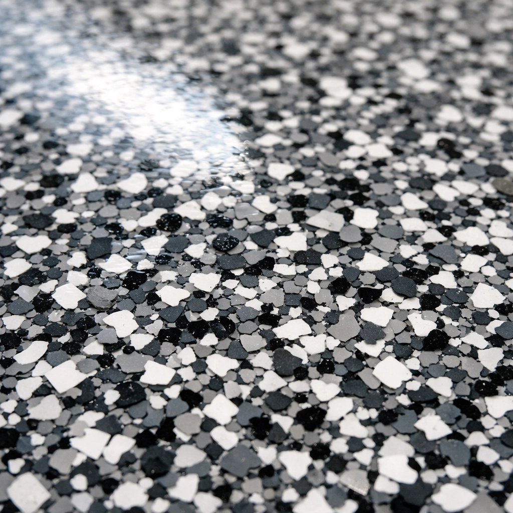 Close-up of decorative charcoal and grey flakes in a high-gloss polyaspartic garage floor coating.