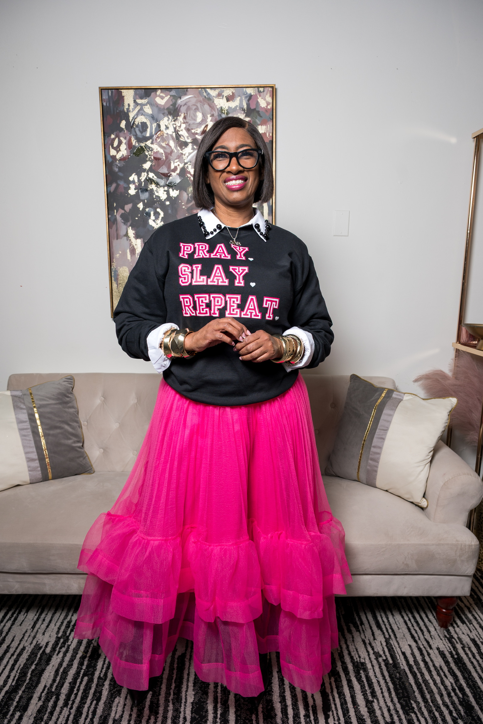 A confident Baltimore woman wearing the “Pray. Slay. Repeat.” sweatshirt and a pink tulle skirt for a stylish spring transition look.