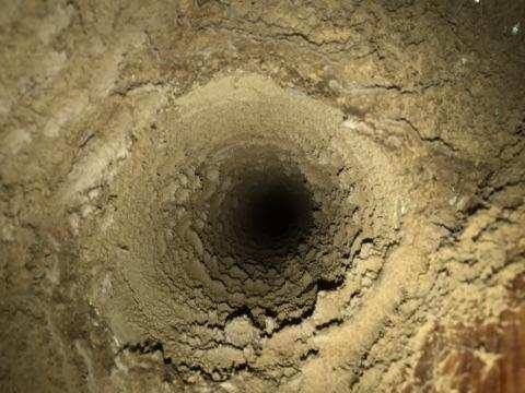 Interior view of an air duct heavily coated with dust, dirt, and debris before professional cleaning.