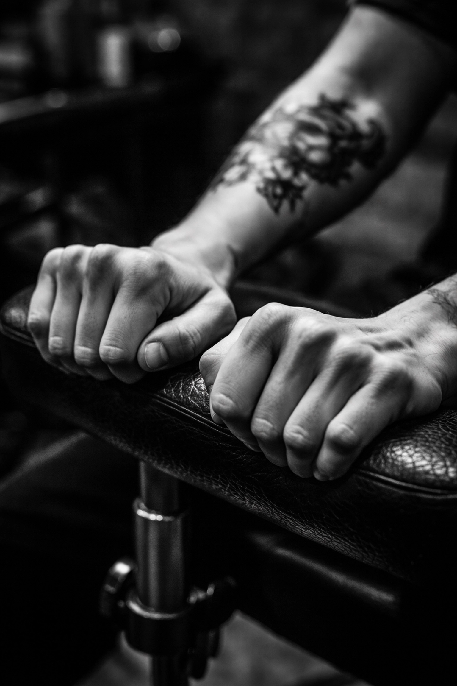 Hands gripping a tattoo chair, resisting the urge to scratch a healing tattoo aftercare in an urban studio.