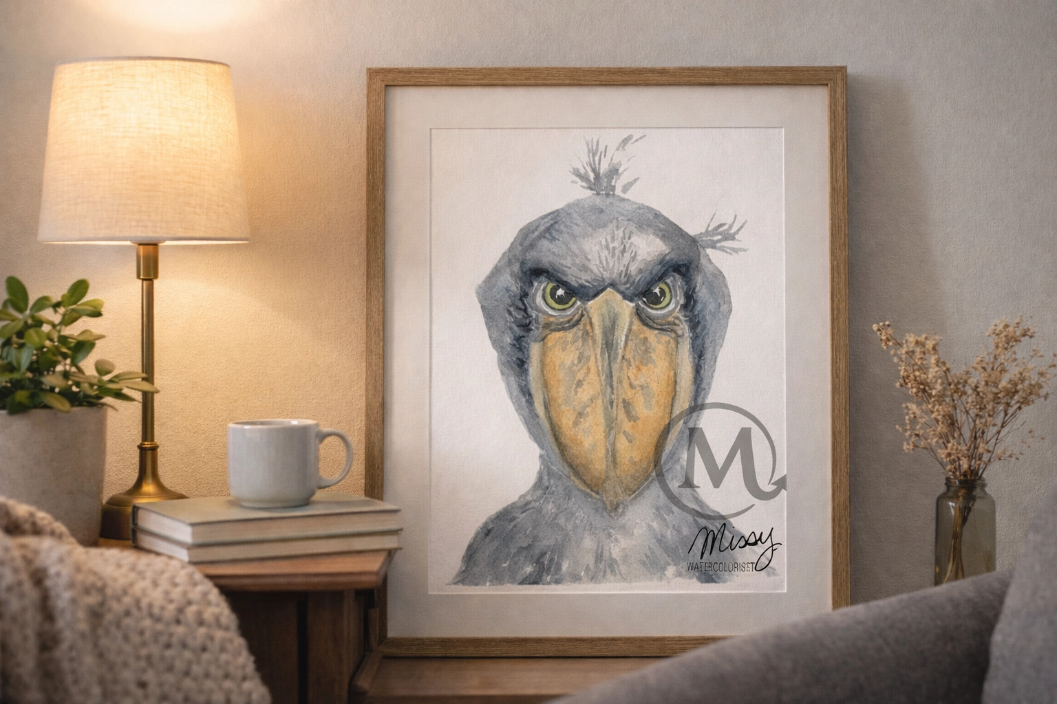 Framed The Shoebill watercolor print by Missy on a side table in a cozy reading nook with a plush armchair.