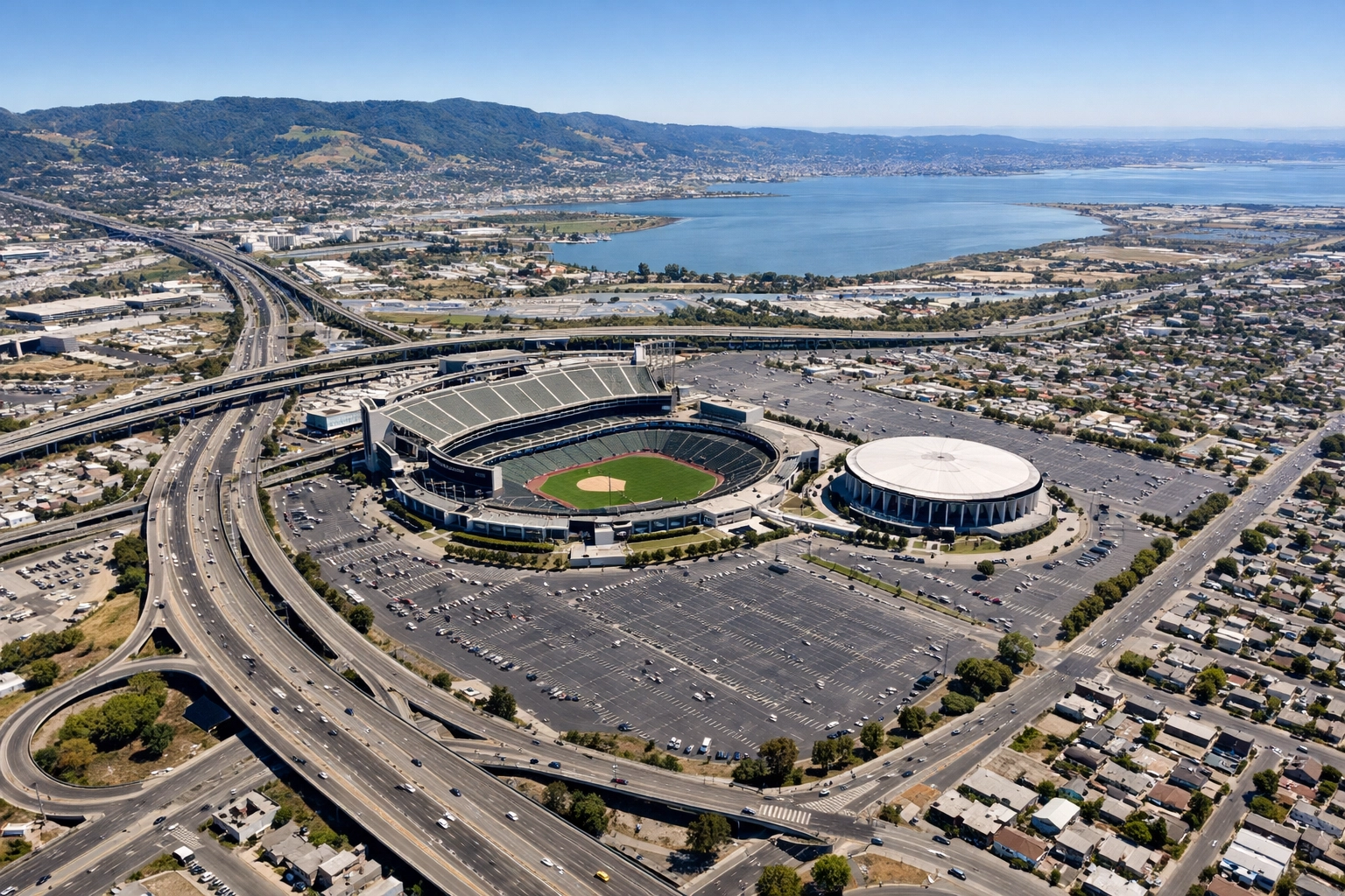 Aerial view of 112-acre Oakland Coliseum site showing stadium, arena, and East Oakland area