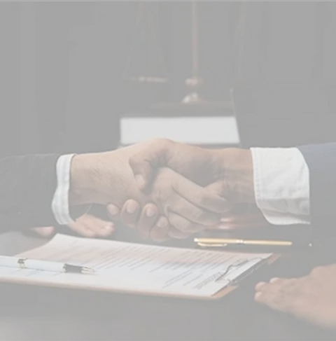 Two individuals shake hands over legal documents, indicating a legal environment focused on trust and resolution.