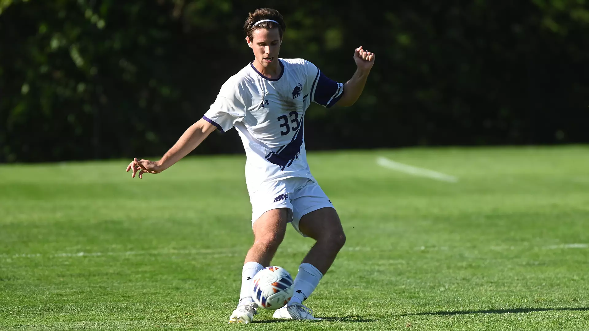 Male College Soccer Player Kicking Ball