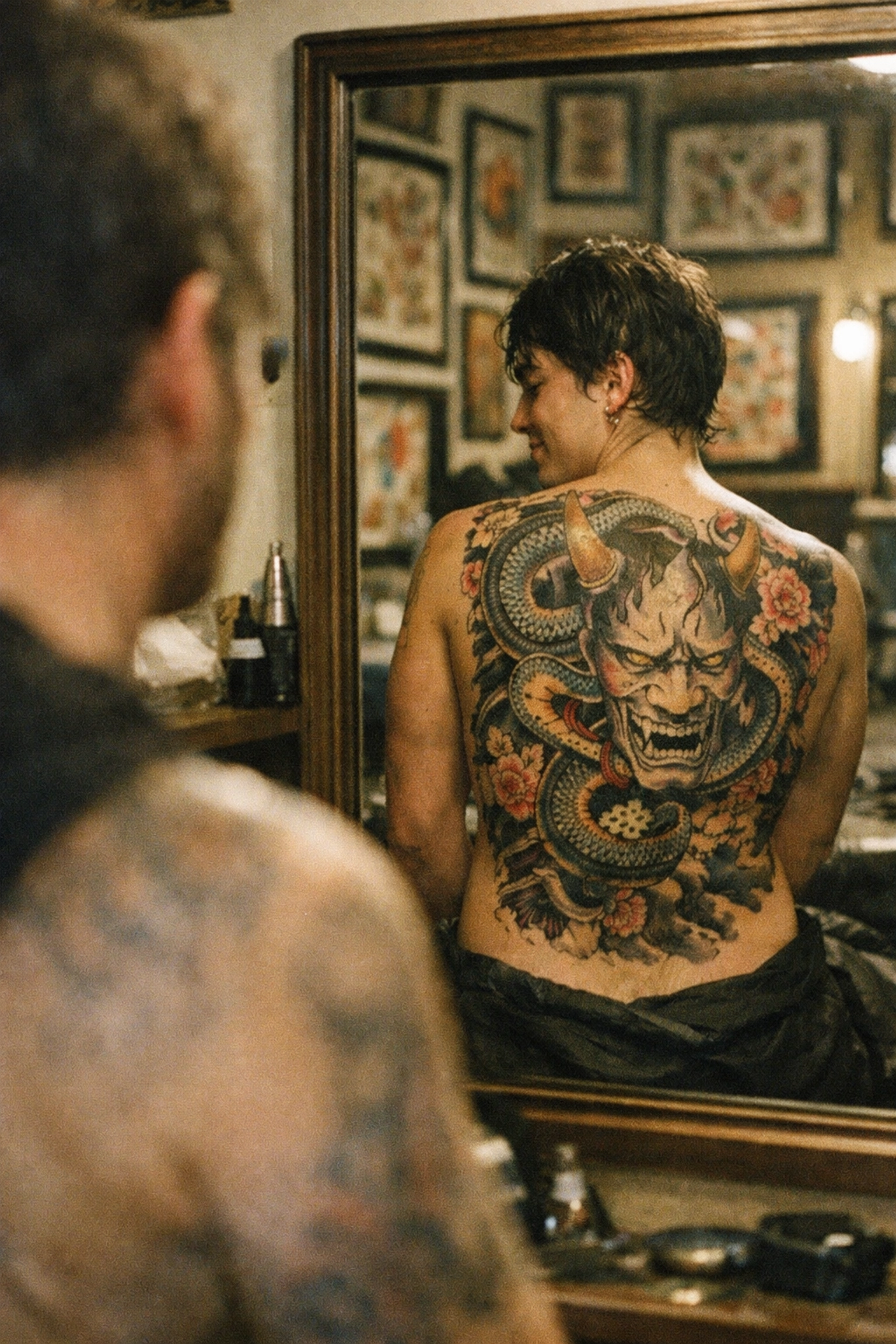 A client admiring their completed custom back tattoo in a Syracuse NY tattoo studio mirror.