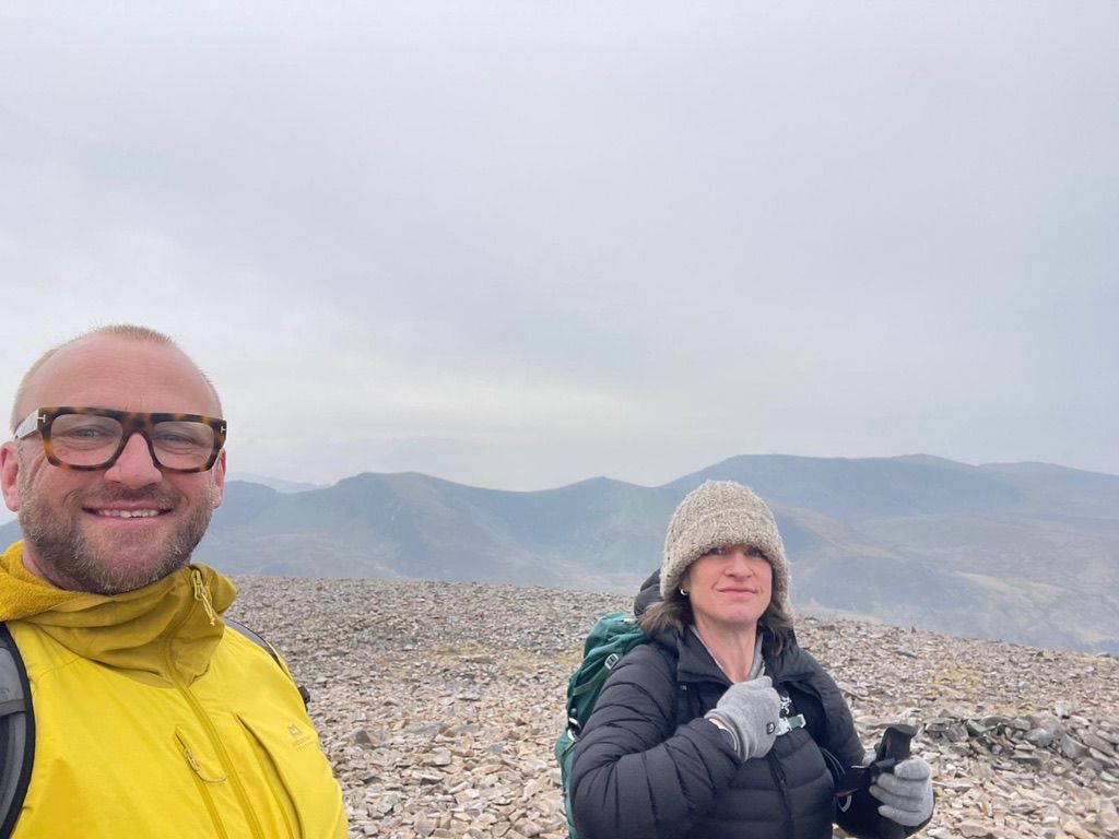 Two hikers on a rocky summit with misty Snowdonia mountains — classic Snowdonia Way vibes.