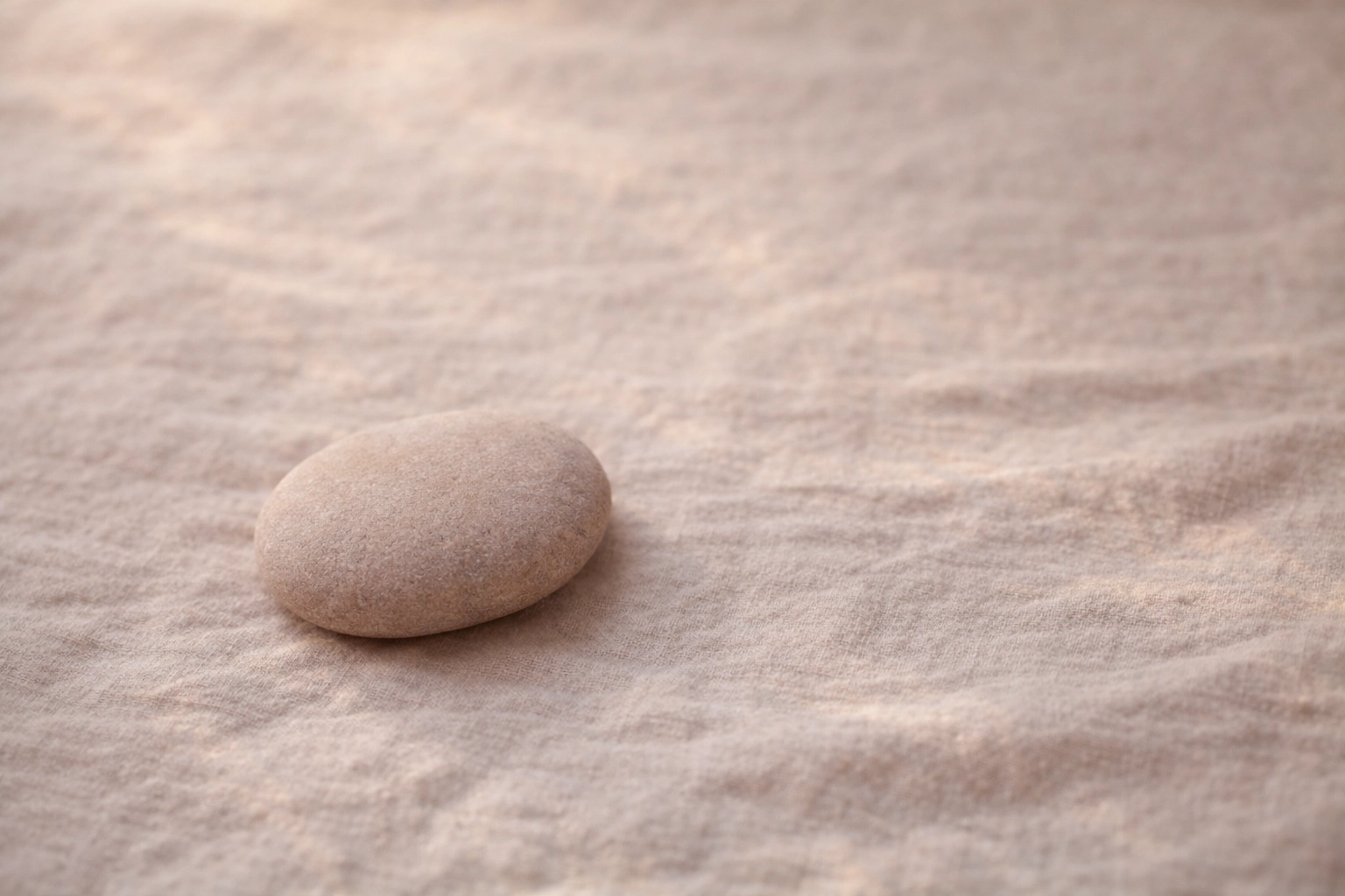 Candid shot of hands resting on soft pink fabric, symbolizing nervous system regulation and embodiment.