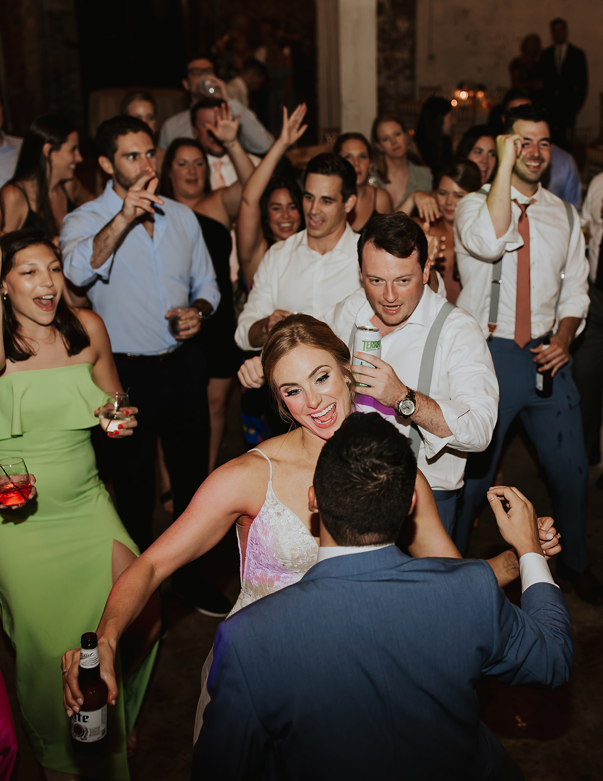 Packed Wedding Dance Floor A lively wedding dance floor filled with guests celebrating joyfully, drinks in hand, with the bride and groom dancing at the center. The event is energized by JAMMIN' DJs' high-energy performance and a professional event atmosphere.