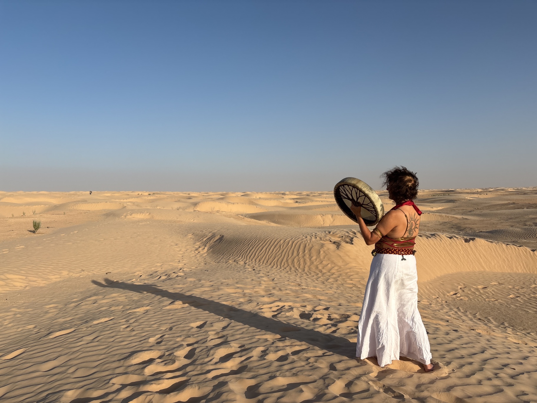 A woman with a tree tattoo on her back stands barefoot in the desert A woman with a tree tattoo on her back stands barefoot in the desert